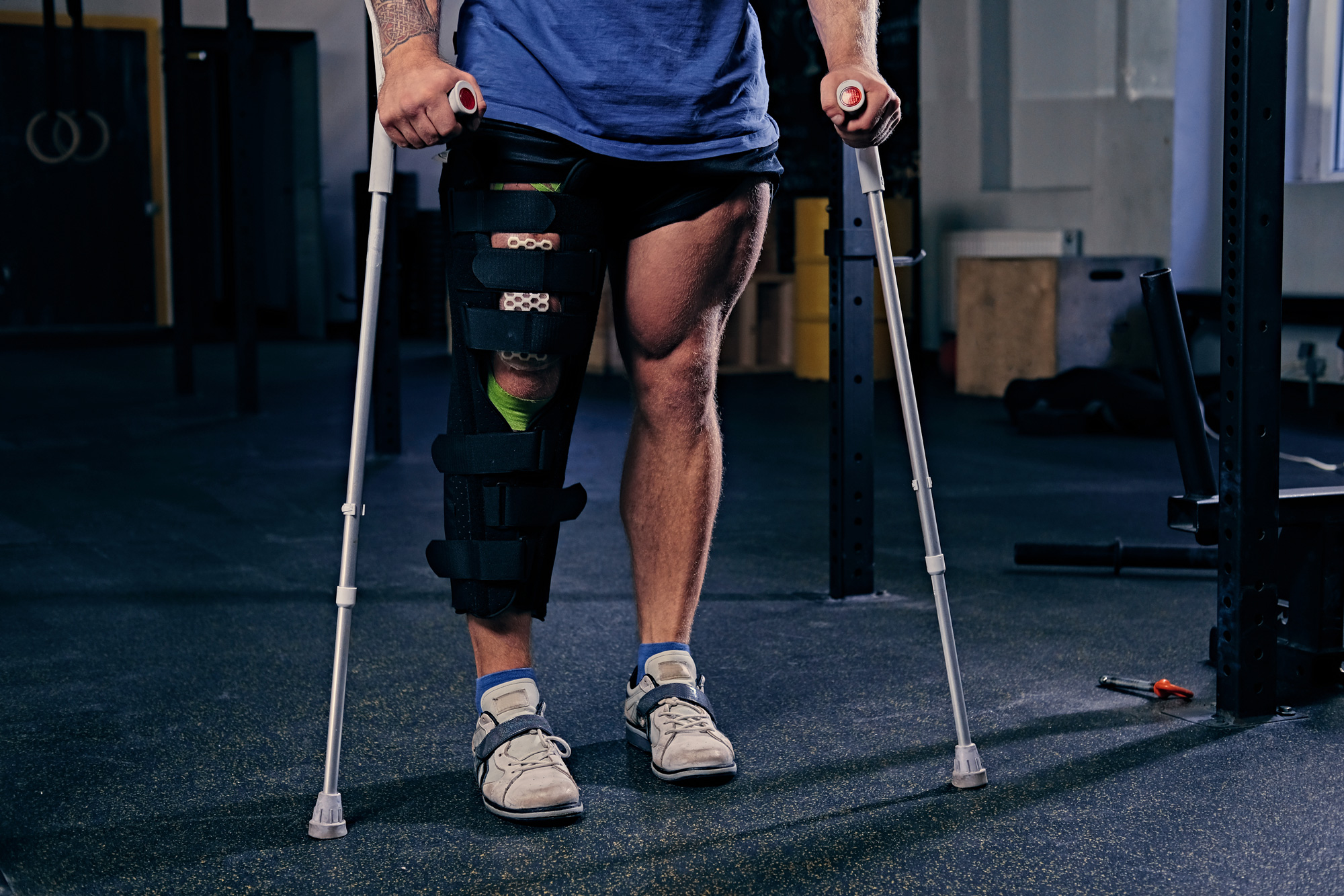 verletztes Bein des Bodybuilders im Verband mit Krücken